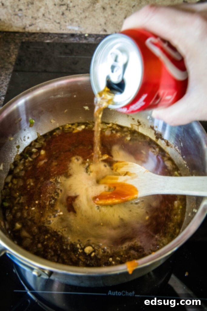 A can of Coca-Cola being poured into a pot filled with other BBQ sauce ingredients, adding its unique flavor.