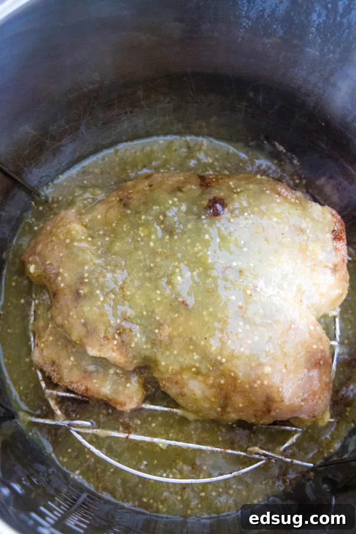 Learn how to cook juicy, flavorful salsa verde chicken in the Instant Pot with just two ingredients, a few spices, and 30 minutes! Salsa verde and chicken breasts expertly combined inside the Instant Pot before cooking, demonstrating the simple setup.