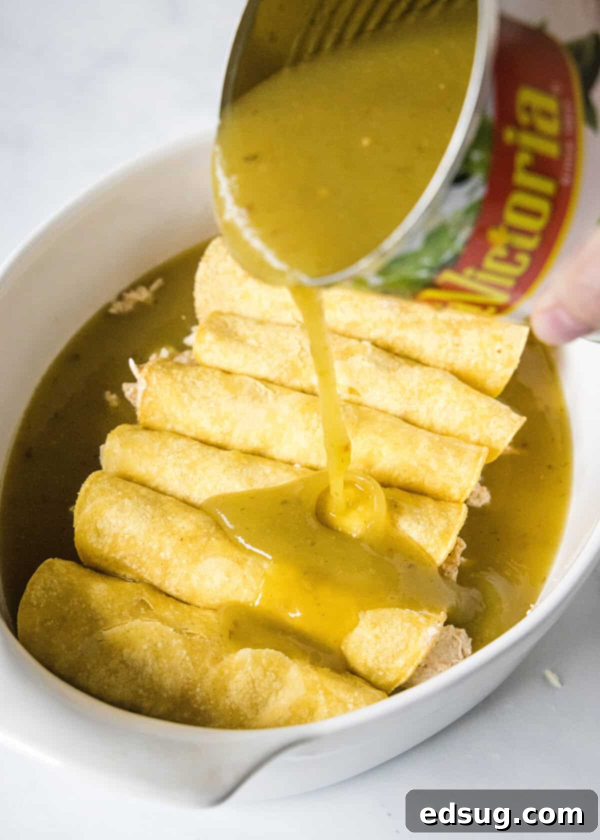 Zesty Green Chile Chicken Enchiladas 7 pouring enchilada sauce over rolled enchiladas in baking pan