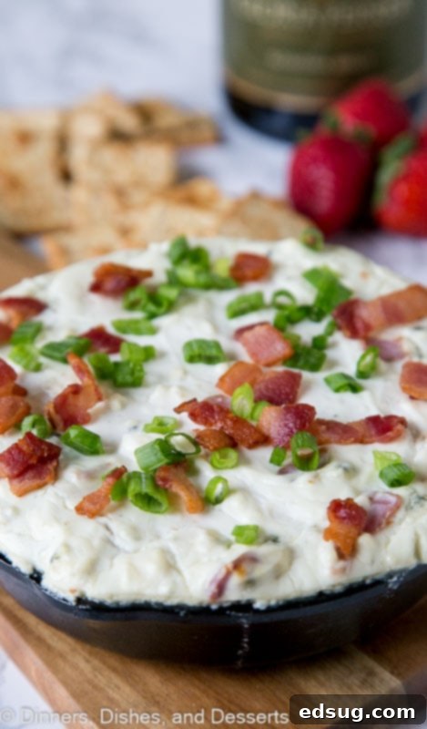 Baked blue cheese dip topped with fresh green onions and crispy bacon in a rustic serving dish