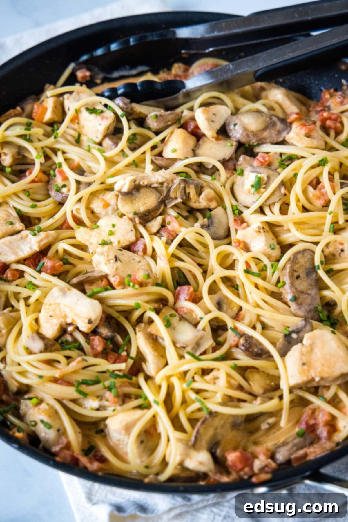 Creamy Tuscan Chicken Pasta 5 Creamy Tuscan chicken pasta simmering in a large skillet, with chicken pieces, mushrooms, and a rich tomato-cream sauce coating the pasta.