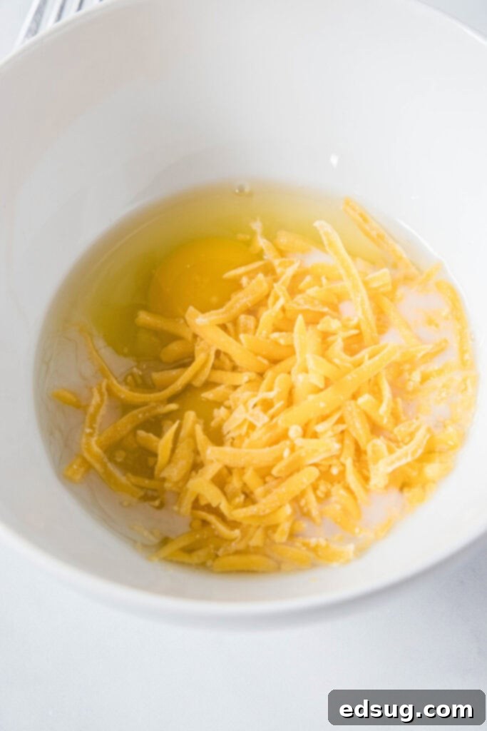 This classic bacon egg and cheese sandwich is the ultimate breakfast, with fluffy eggs, melty cheese, crispy bacon, and a toasted bagel. A bowl with eggs and shredded cheese