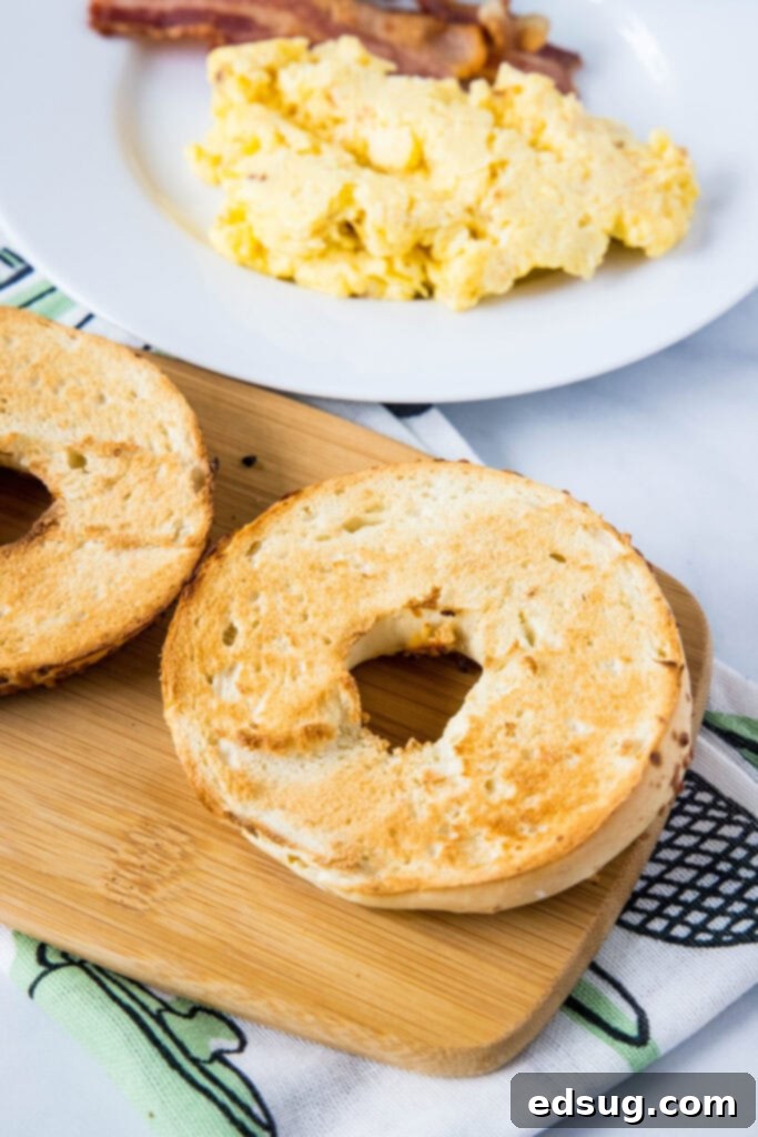 This classic bacon egg and cheese sandwich is the ultimate breakfast, with fluffy eggs, melty cheese, crispy bacon, and a toasted bagel. A toasted bagel next to a plate of eggs and bacon