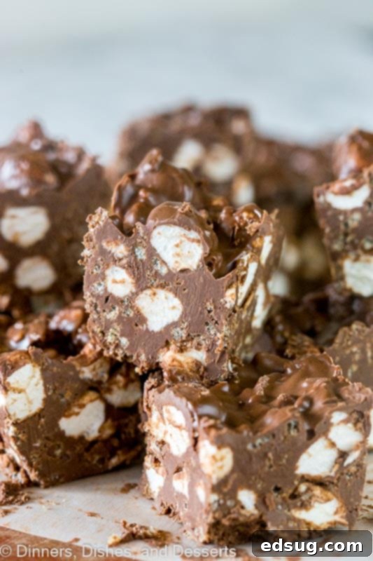 Decadent Chocolate Avalanche Bars 2 Chocolate Avalanche Bars - super easy no bake avalanche cookies turned into even easier bars made with 3 kinds of chocolate! A close-up shot of square-cut chocolate bars with visible marshmallows and rice crispy cereal.