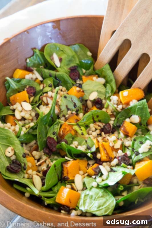 A bowl of salad with Israeli couscous, butternut squash, spinach, cranberries and pecans