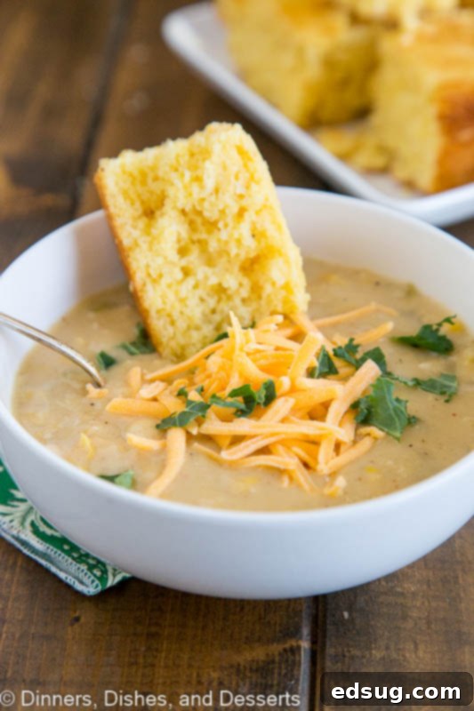 Southwestern Chicken Corn Chowder served in a white bowl with a side of cornbread, garnished with fresh cilantro and shredded cheese.