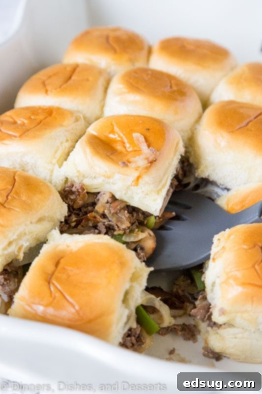 Philly Cheesesteak Sliders - little cheesesteak sliders are stuffed with sauteed onions, peppers, mushrooms, and lots of melty cheese! Great for a party, game day, or a fun and easy dinner! A dish filled with warm, golden-brown Philly Cheesesteak Sliders, showcasing the melty cheese and savory fillings.