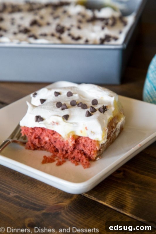 Luscious Red Velvet Poke Cake 2 A perfectly sliced piece of Beet Red Velvet Poke Cake, displaying its rich, natural red color from beets, layered with creamy vanilla pudding and topped with fluffy whipped cream, resting on a rustic wooden table.