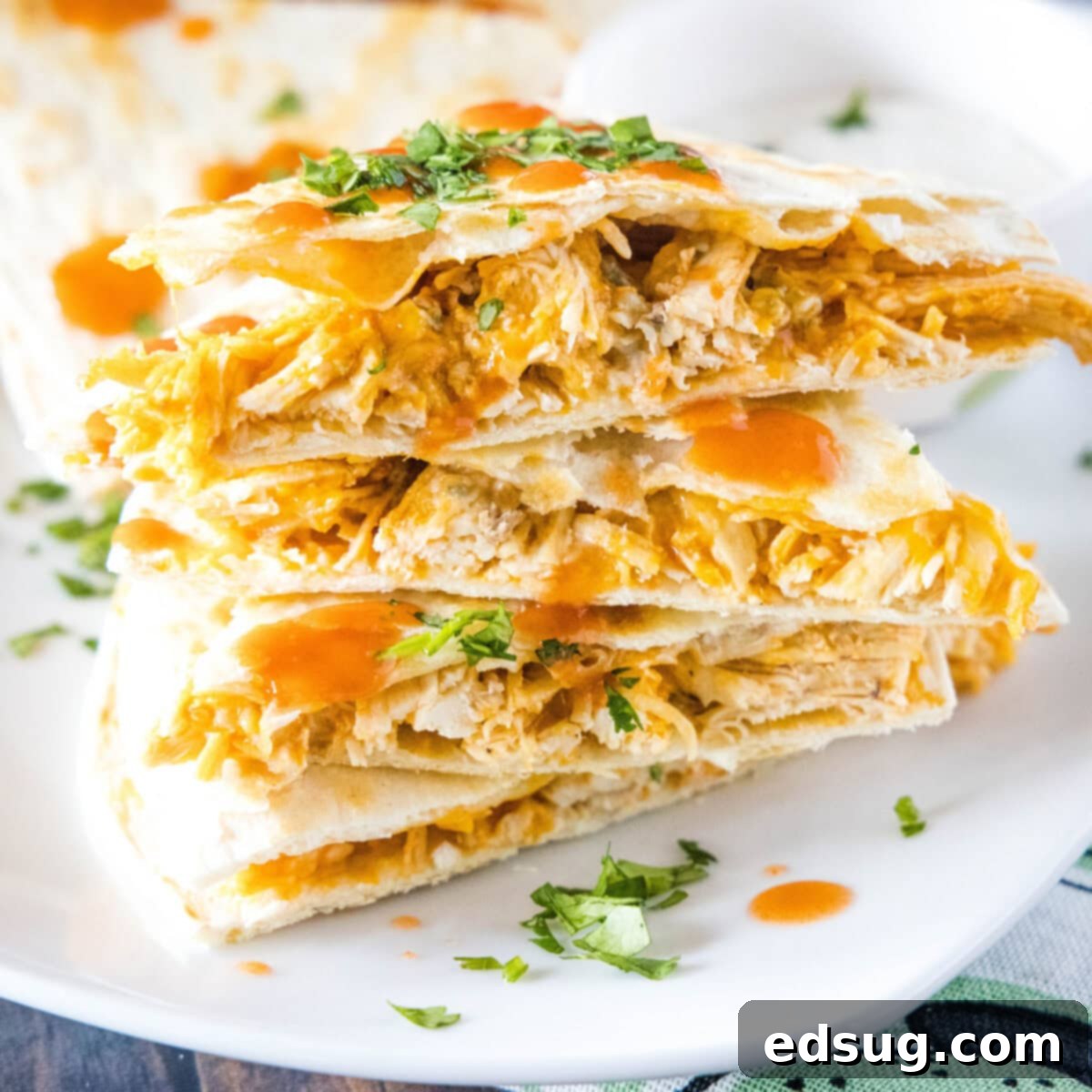 Cluck-Worthy Chicken Meals 32 A stack of slices of buffalo chicken quesadillas on a plate, topped with cilantro