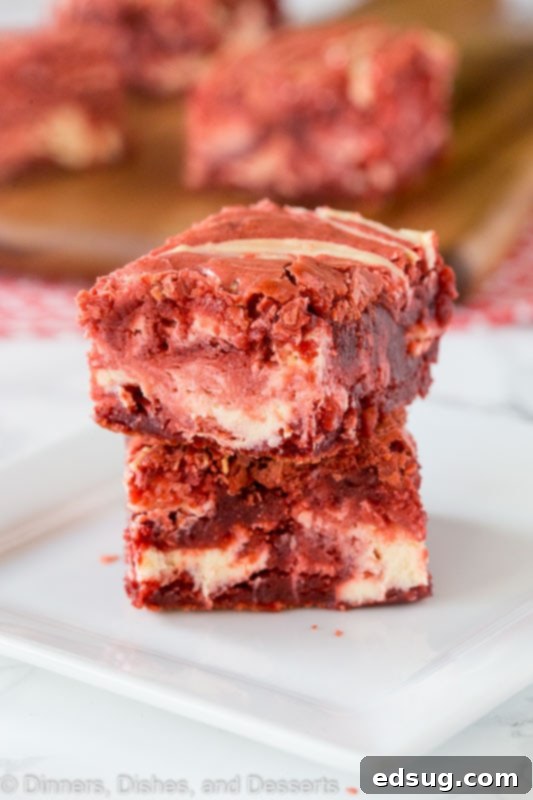 A close up of red velvet brownies with cream cheese swirl, showcasing the vibrant red color and creamy white swirls.