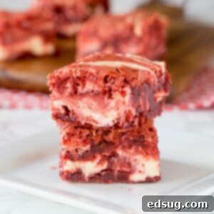 Swirled Red Velvet Cheesecake Brownies 6 red velvet brownies with cream cheese swirl stacked on a plate
