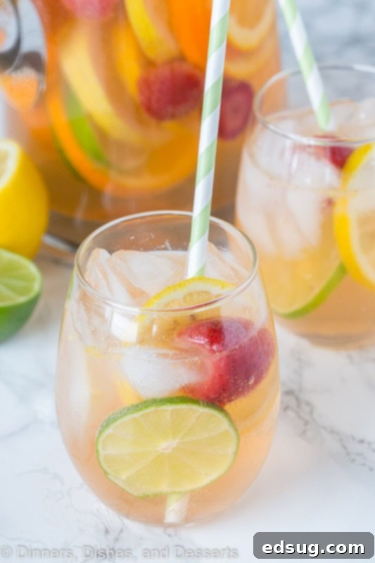 White wine sangria with citrus slices and berries, garnished with mint.