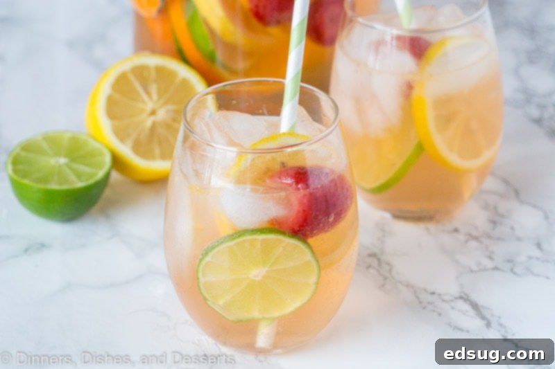 Close-up of hands mixing fruit and wine in a large pitcher to make sangria.