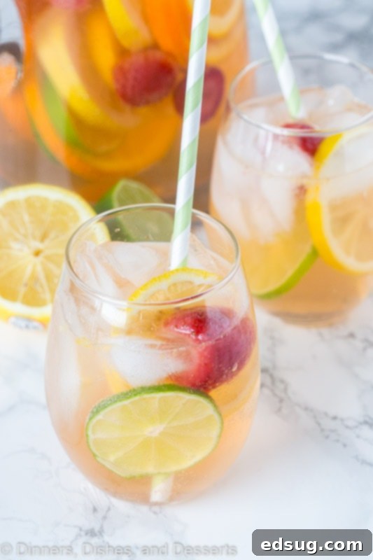 A glass of white wine sangria with fruit and ice, ready to drink.