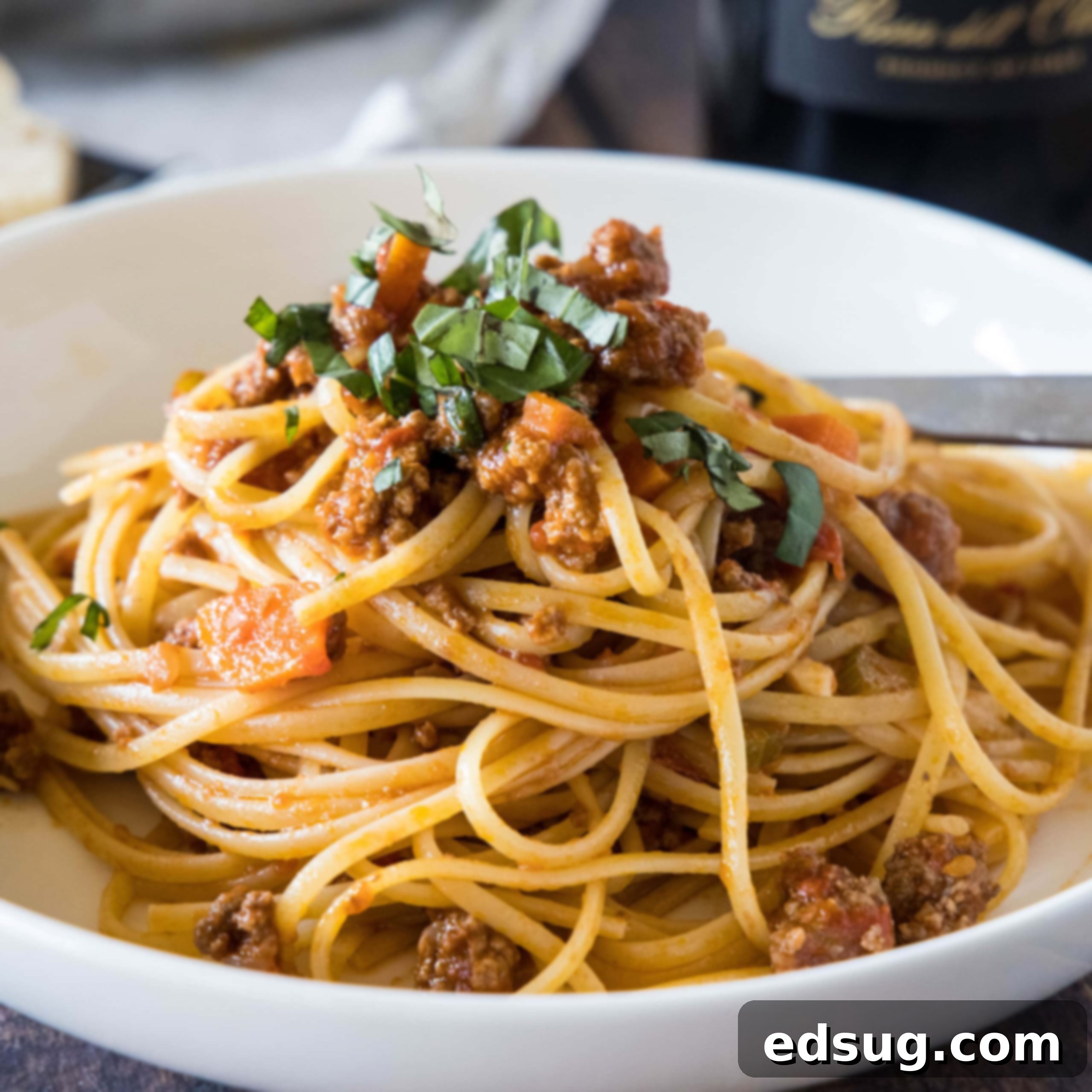 Beef ragu served with spaghetti in a white bowl.