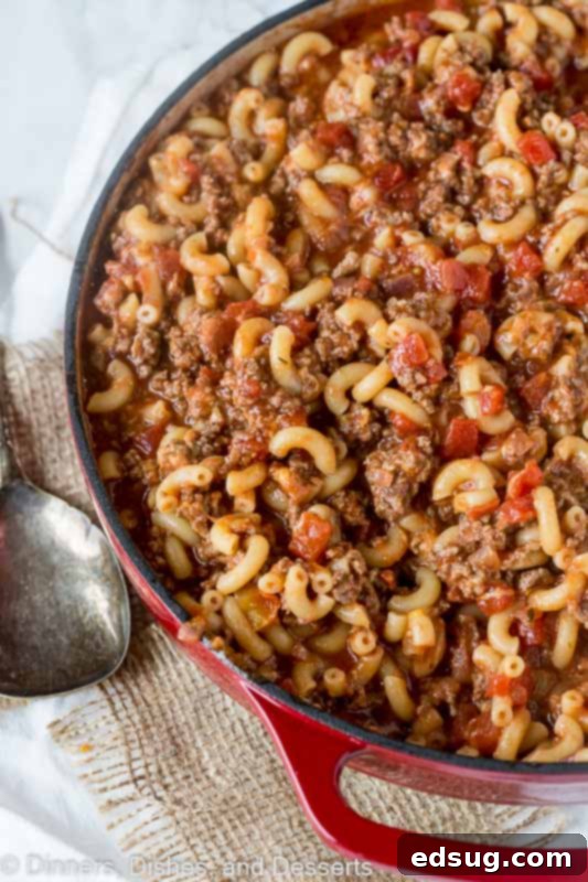 Overhead view of a dutch oven filled with goulash, next to a spoon