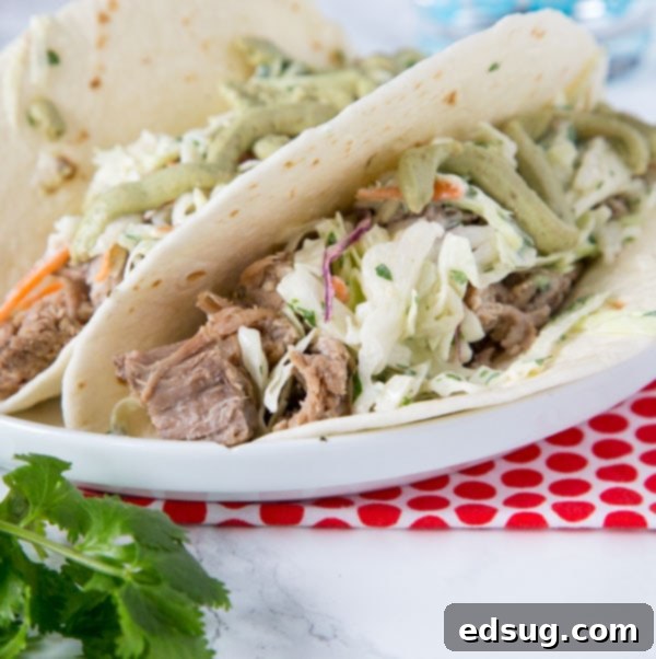 Instant Pot Pork Tacos - these pulled pork tacos are super tender and so delicious. Topped with a creamy Mexican slaw and avocado sauce!