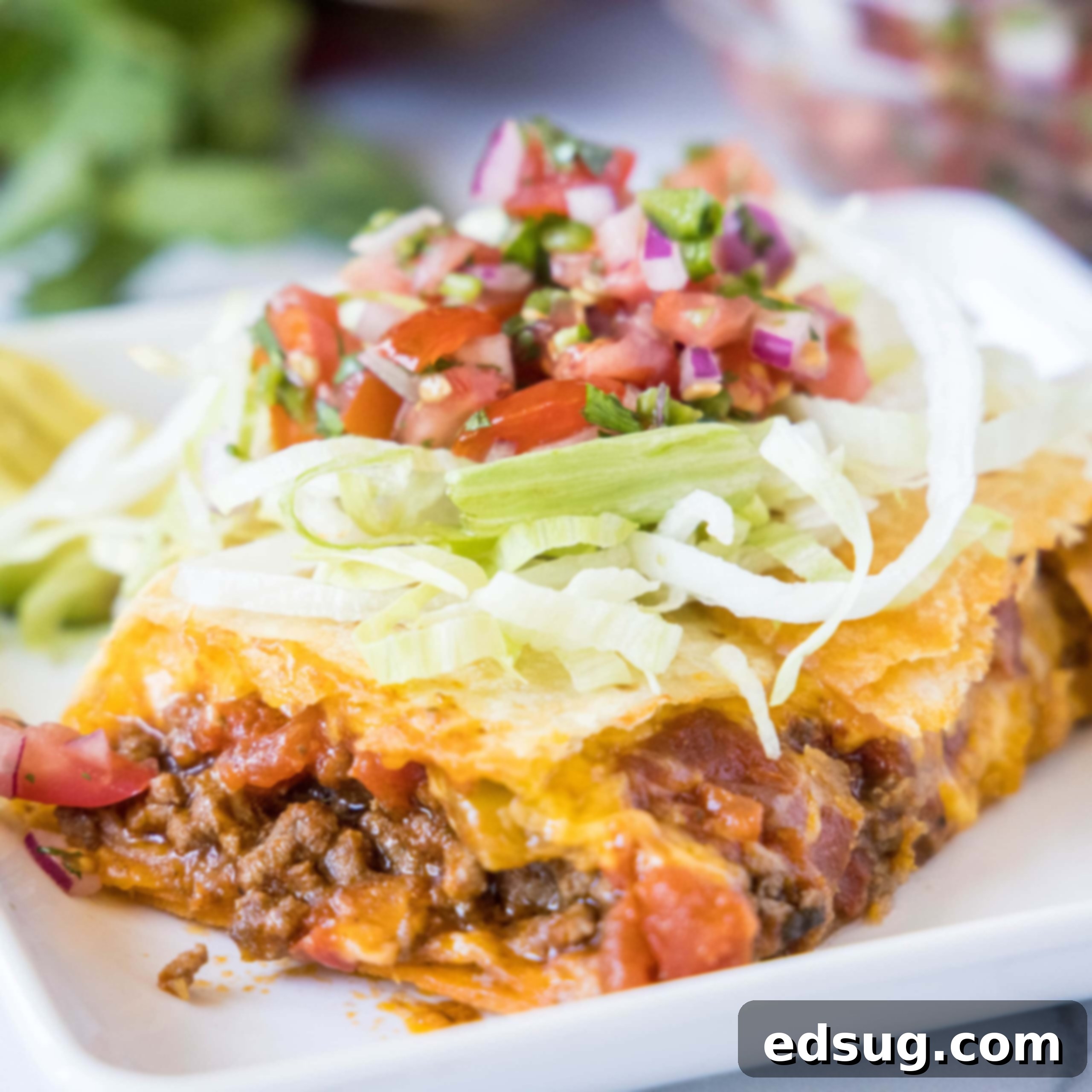 Close up of a sheet pan taco on a plate, garnished with fresh cilantro and lime.