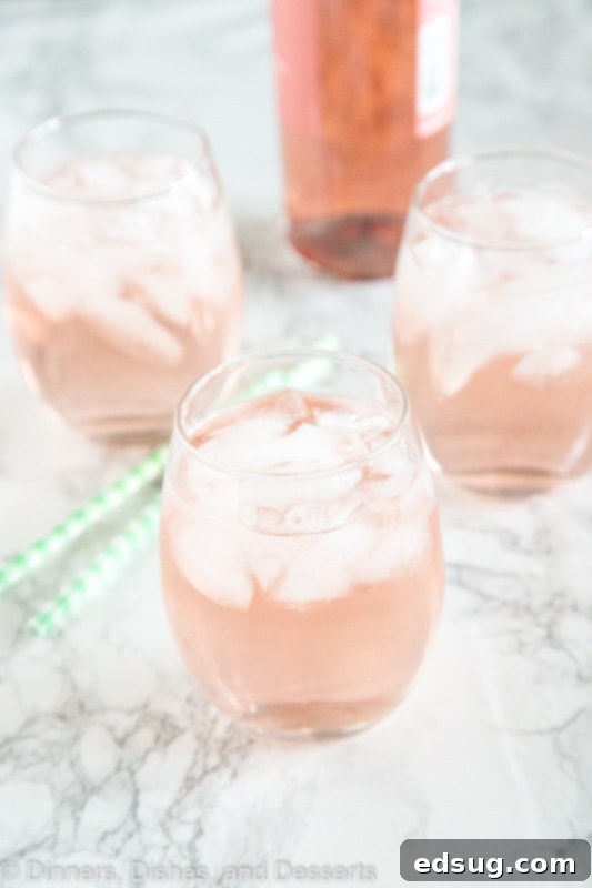 Close-up of a glass of rosé wine spritzer being prepared.