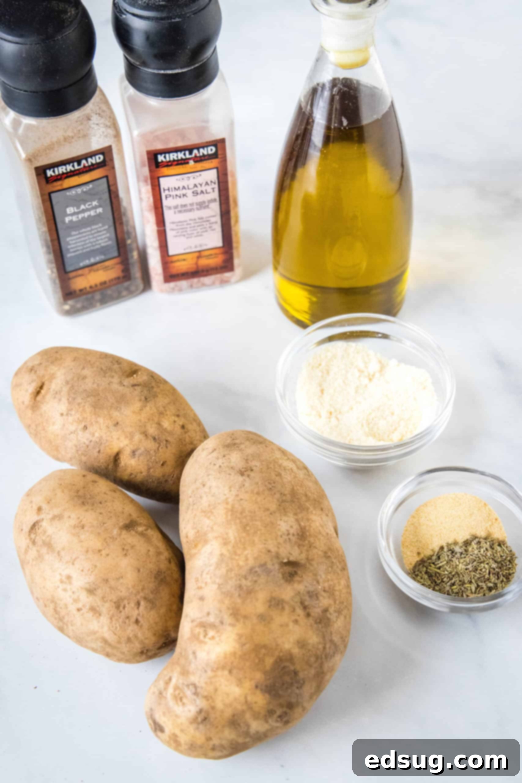 Make perfectly golden, crispy oven roasted potatoes as an easy side dish or appetizer! All it takes is olive oil and a handful of spices. Ingredients for oven roasted potatoes laid out on a cutting board.