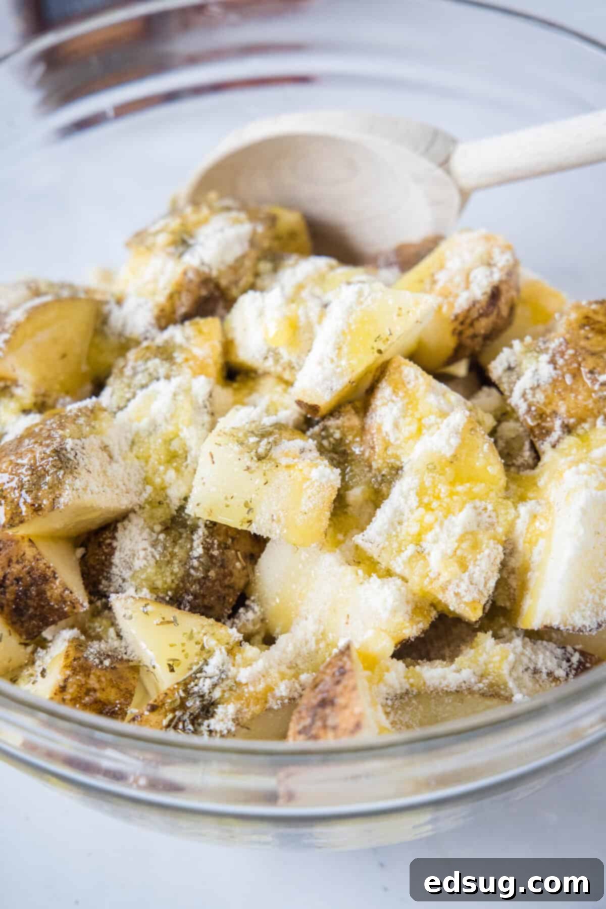 Make perfectly golden, crispy oven roasted potatoes as an easy side dish or appetizer! All it takes is olive oil and a handful of spices. Cubed potatoes tossed with olive oil and seasonings in a bowl, ensuring even coating.