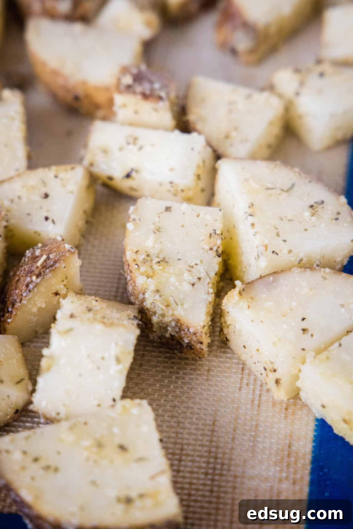 Make perfectly golden, crispy oven roasted potatoes as an easy side dish or appetizer! All it takes is olive oil and a handful of spices. Close up of seasoned potatoes spread in a single layer on a baking sheet, ready for roasting.