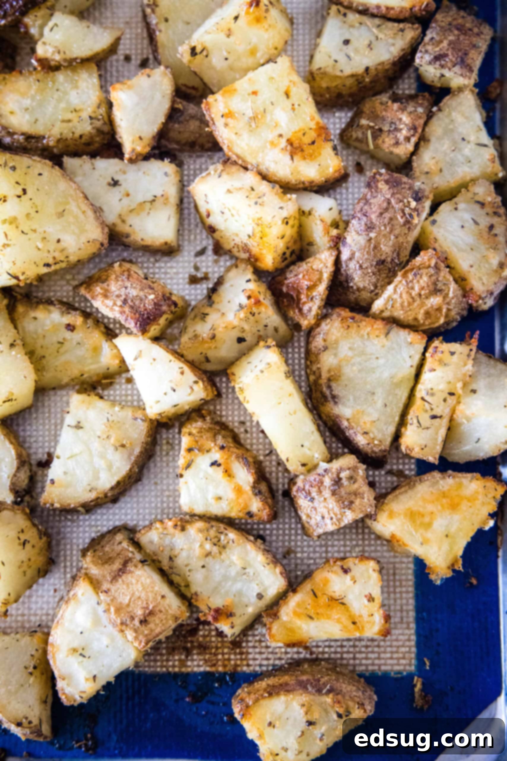 Make perfectly golden, crispy oven roasted potatoes as an easy side dish or appetizer! All it takes is olive oil and a handful of spices. Overhead view of oven roasted potatoes spread on a baking sheet, golden and ready to serve.