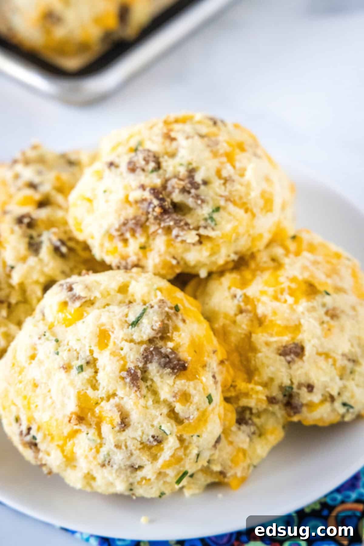 Cheesy Sausage Biscuit 5 An overhead view of a plate filled with golden-brown cheese and sausage biscuits, highlighting their delicious and appetizing appearance.