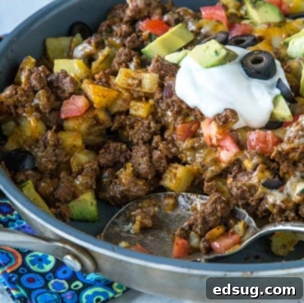 Mexican Skillet Potatoes in a pan, loaded with taco meat, salsa, and cheese.