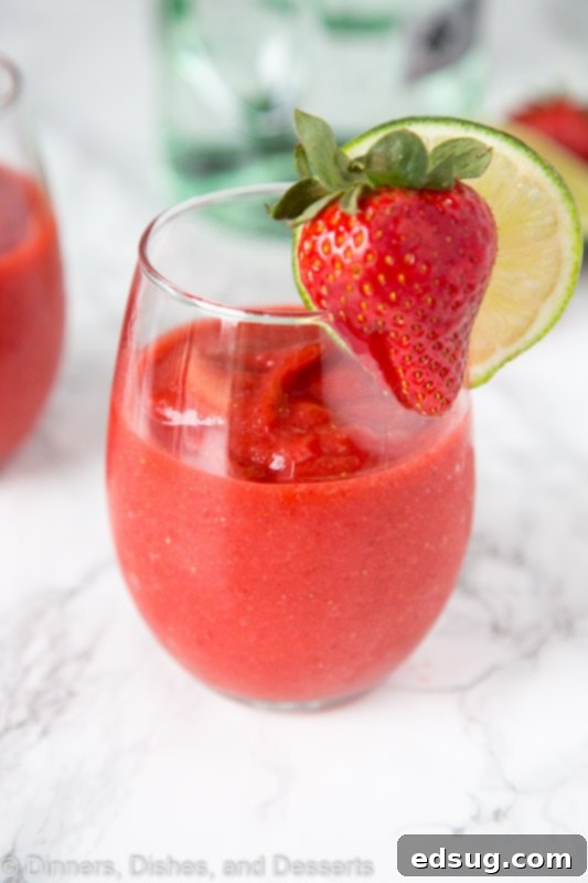 Frosted Strawberry Daiquiri 2 A beautifully garnished glass of Frozen Strawberry Daiquiri with fresh strawberries and a lime slice, perfect for summer.