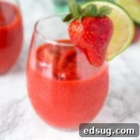 Frosted Strawberry Daiquiri 6 A glass of frozen strawberry daiquiri with a strawberry and lime slice