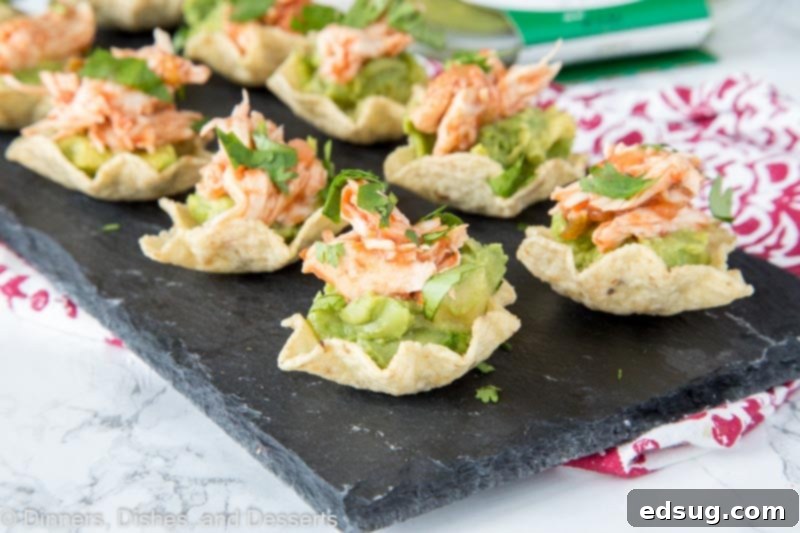 Zesty Avocado Chicken Poppers 4 A vibrant platter of Avocado Chicken Bites, showcasing creamy guacamole, spicy shredded chicken, and fresh cilantro on individual tortilla scoops, ready for a party.