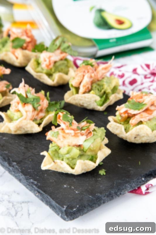 Zesty Avocado Chicken Poppers 5 Close-up of a single Avocado Chicken Bite, perfectly assembled on a tortilla scoop with visible layers of guacamole and shredded chicken, garnished with cilantro.