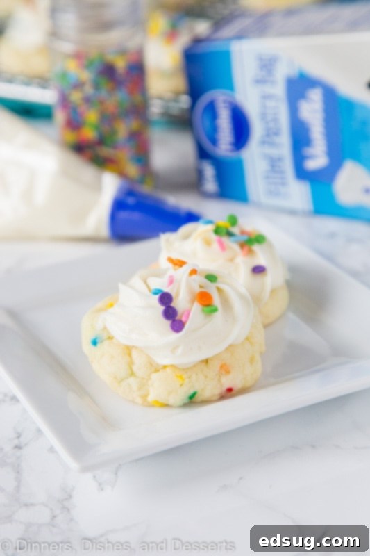 Sparkle-Topped Funfetti Cake Mix Cookies 5 An appetizing overhead shot of frosted Funfetti Cake Mix Cookies, generously topped with vanilla frosting and an explosion of colorful sprinkles, arranged on a plate.