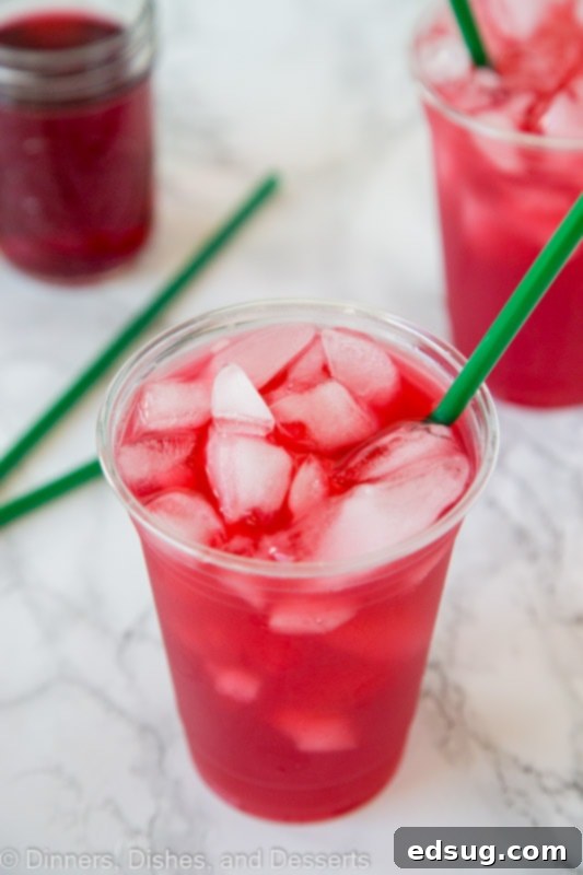 A close-up shot of a glass of iced Passion Tea Lemonade with a straw