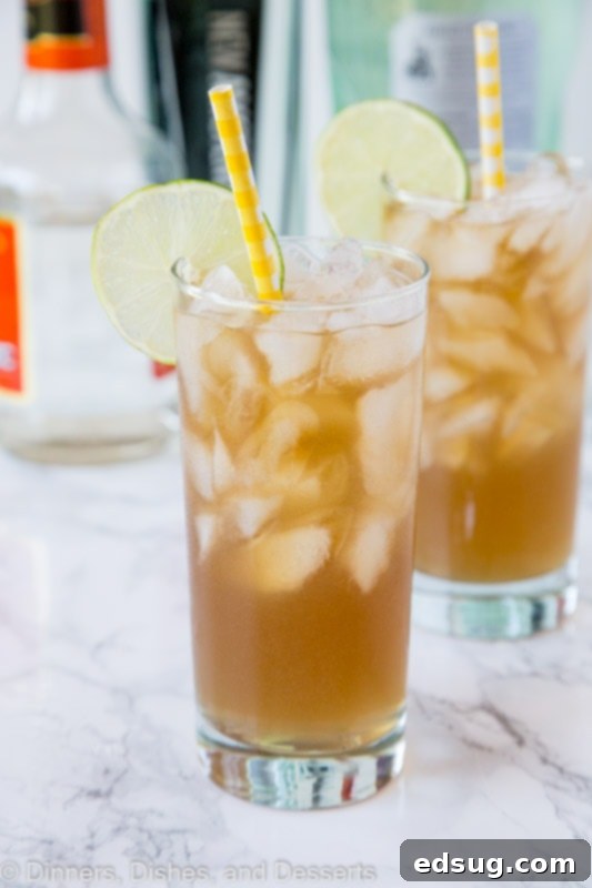 A close up of long island iced tea in a tall glass with ice and a lemon slice, highlighting its refreshing appearance.
