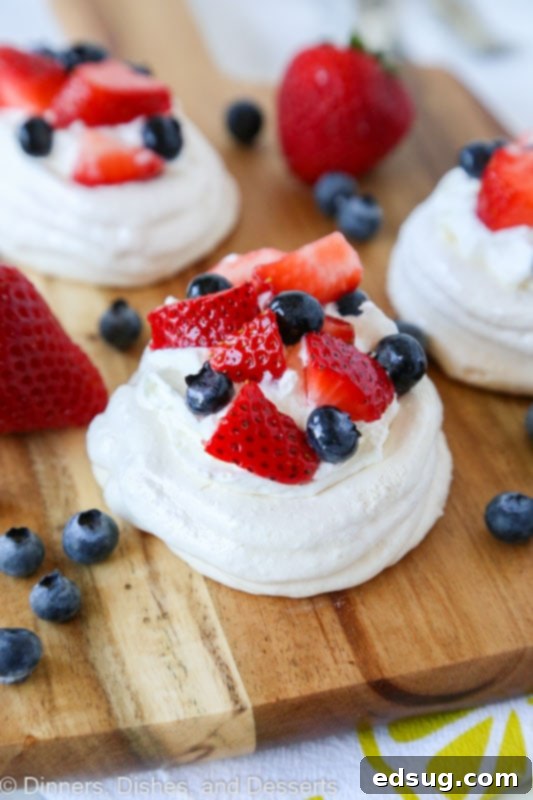 Easy Mini Pavlova Recipe 3 A beautifully presented mini pavlova on a wooden board, garnished with an array of colorful fresh berries.