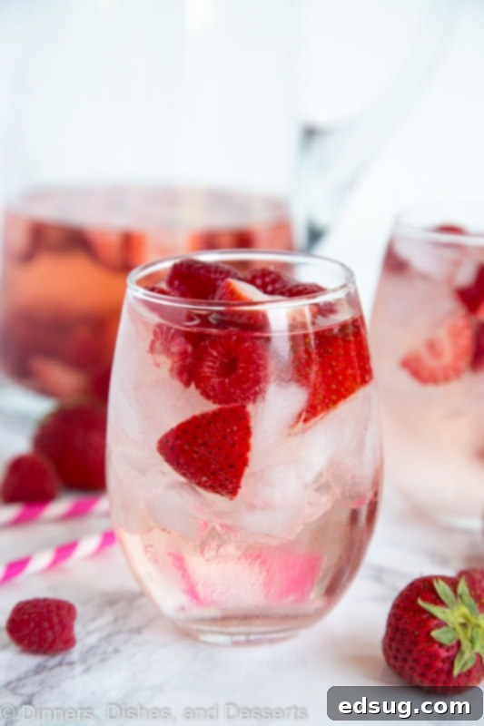 Blushing Berry Rose Sangria 2 A close up of a glass cup on a table, with Sangria and Wine
