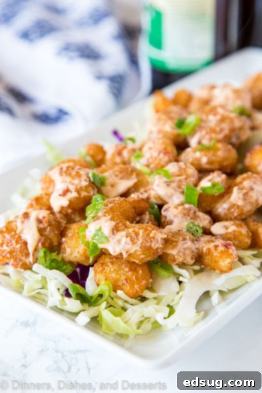 Crispy Bang Bang Shrimp with Sweet Chili Sauce 4 A close up of a plate of fried shrimp drizzled with creamy Bang Bang sauce and garnished.