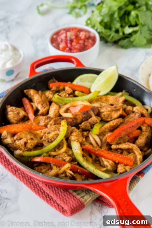 A serving of cooked chicken fajitas with various toppings like salsa, sour cream, and avocado.