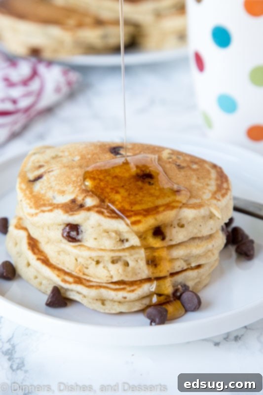 A stack of chocolate chip banana pancakes drizzled with maple syrup.