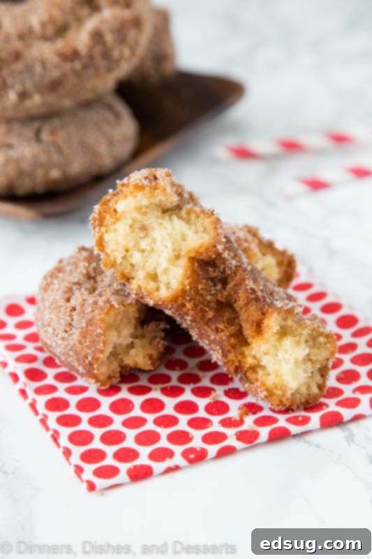 Half of an apple cider donut on a rustic wooden table, showing its cake-like texture.