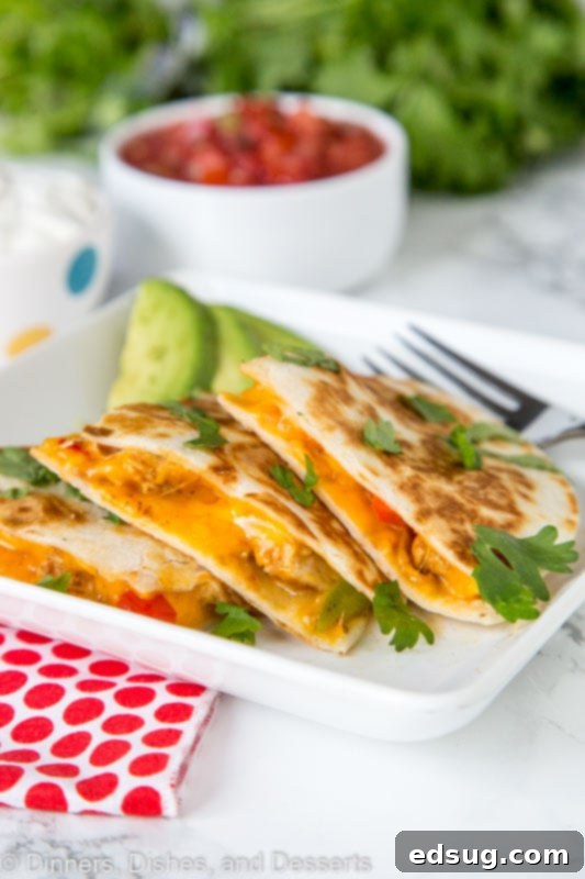 Chicken Fajita Quesadilla Supreme 2 Close-up of a golden-brown chicken fajita quesadilla sliced on a plate, revealing melted cheese and seasoned chicken and vegetables.