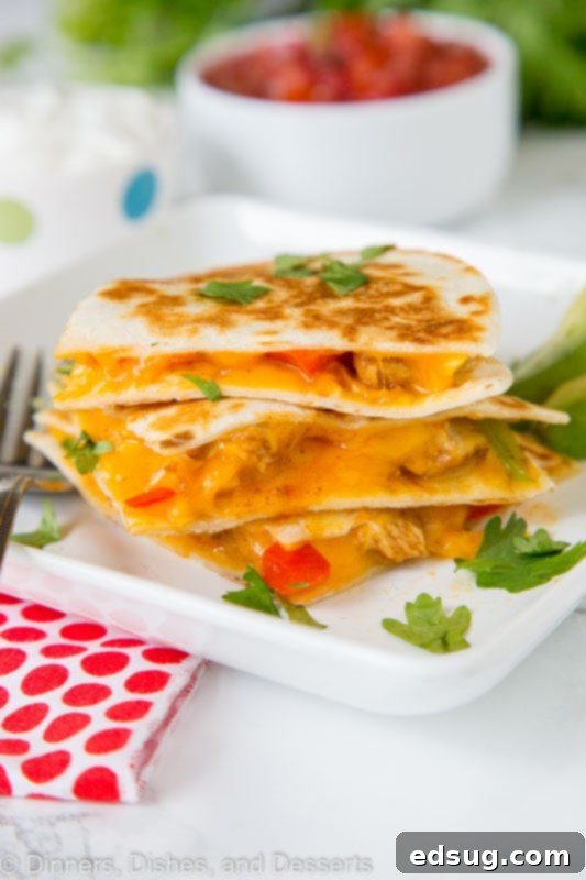 Chicken Fajita Quesadilla Supreme 3 A stack of golden-brown chicken fajita quesadillas on a plate, garnished with fresh cilantro.