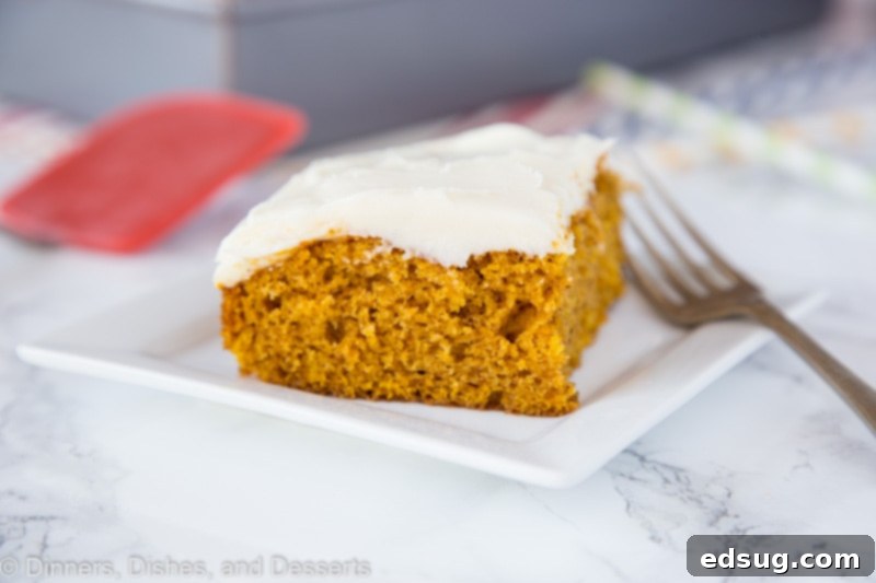 A generous serving of pumpkin cake topped with cream cheese frosting, garnished with a sprinkle of cinnamon.
