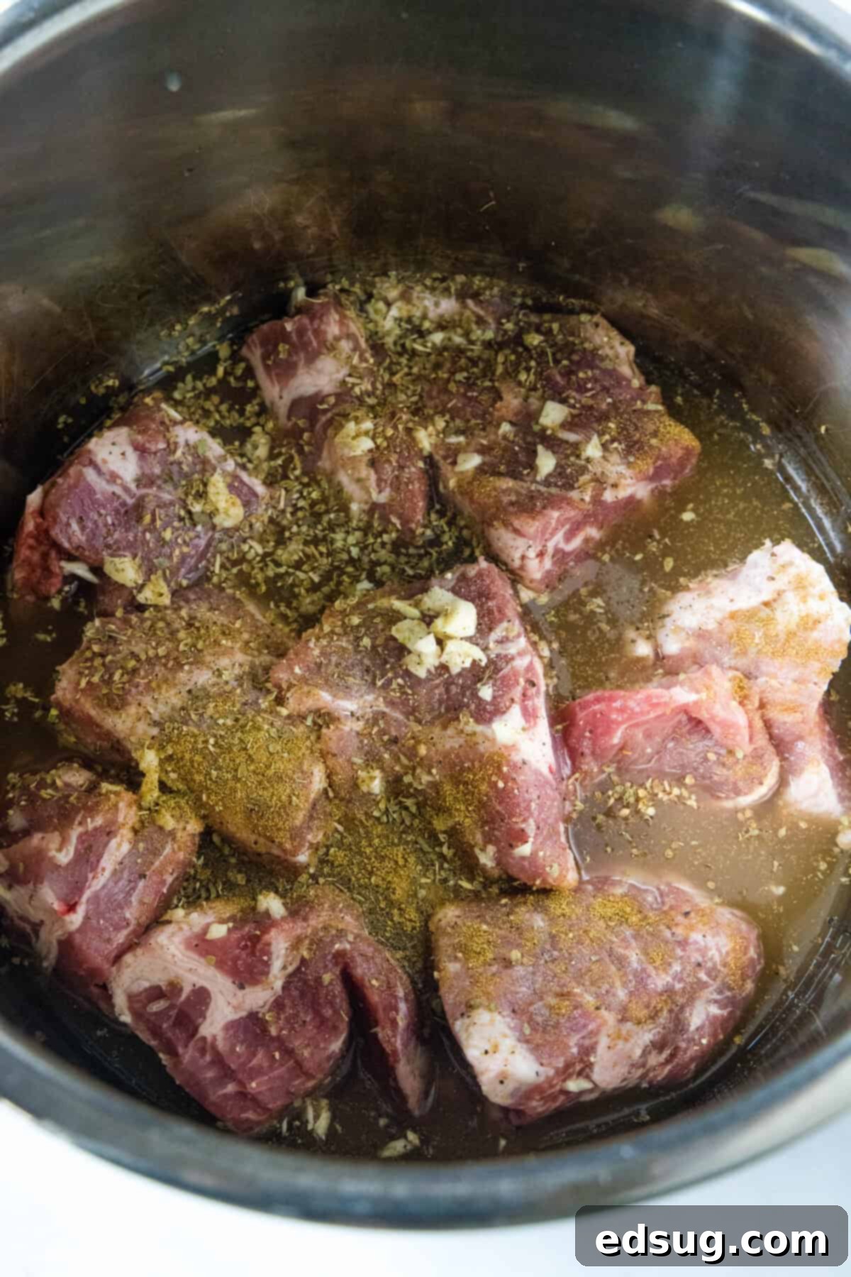 Instant Pot Pork Taco Perfection 4 Adding cut pork shoulder chunks to an Instant Pot alongside various spices and liquids.