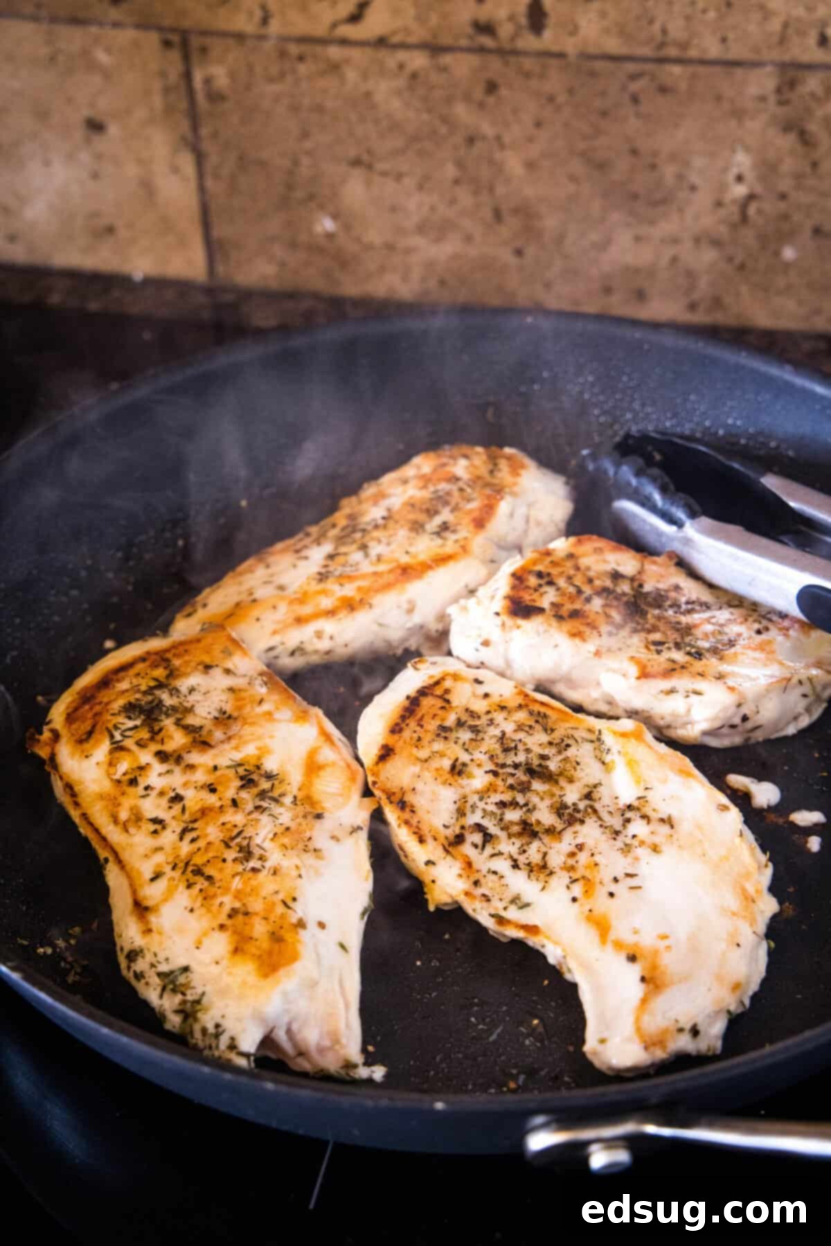 The initial step of searing chicken breasts for the one pan lemon herb chicken with orzo dinner. Seared chicken breasts achieving a golden-brown crust in a hot skillet.