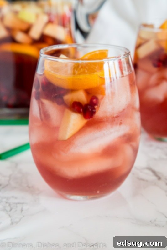 Festive Christmas Sangria 2 A beautifully garnished glass of Christmas Sangria, showcasing the vibrant white wine and festive fruit medley, ready for a holiday toast.