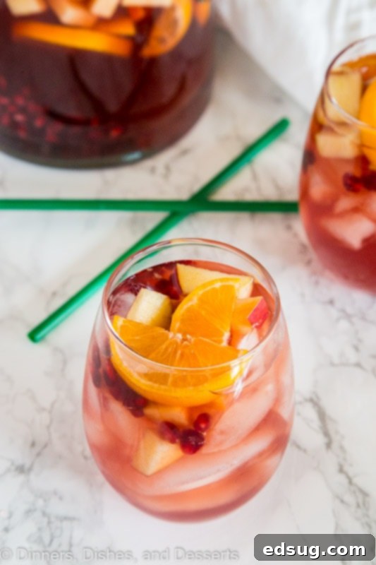 Festive Christmas Sangria 4 A festive glass of white wine Christmas Sangria, garnished with fresh fruits, capturing the essence of holiday cheer and deliciousness.