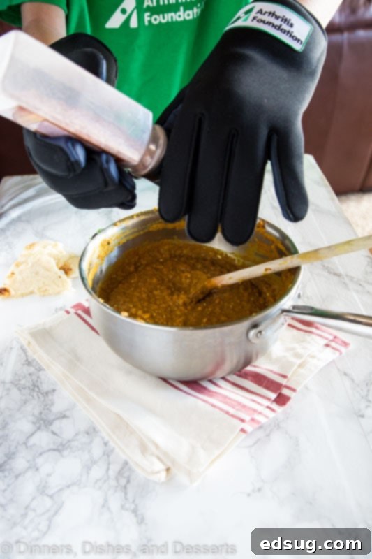 Aromatic Indian Daal 5 A hand wearing an arthritic glove attempting to put salt into a bowl of soup, highlighting challenges faced by arthritis sufferers.